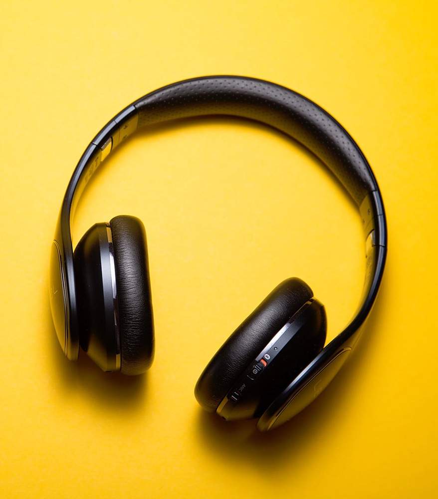 Black wireless noise-cancelling headphones on a yellow background